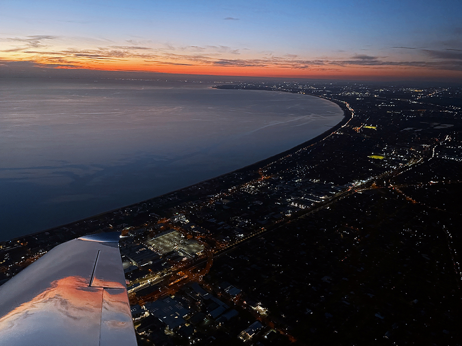 Aerial view of Melbourne coastline at dusk from a light aircraft, illustrating the visual conditions suitable for Night VFR flight.