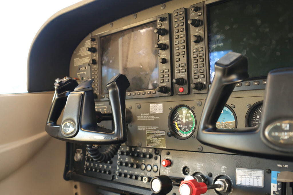 Close-up view of an aircraft cockpit showing dual controls and avionics—highlighting the advanced systems used in both private and commercial pilot training.