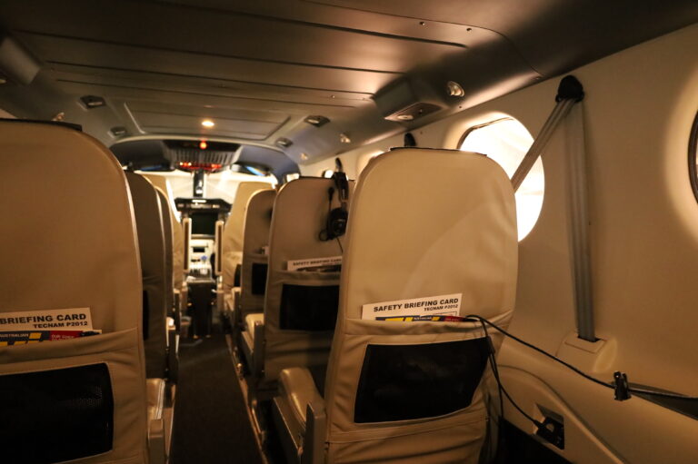 Interior cabin view of a Tecnam P2012 aircraft showing seating layout and safety briefing cards, relevant to training in multi-engine aircraft for an Instrument Rating