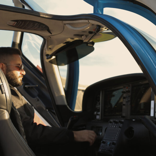 Pilot seated inside a modern light aircraft cockpit, preparing flight systems before departure with the canopy door open.